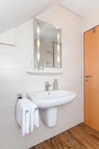 Baño blanco con lavabo y espejo en Pension Nordkap, en Bensersiel