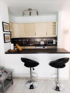 a kitchen with two black stools at a counter at 91 Port Royale Los Cristianos in Los Cristianos