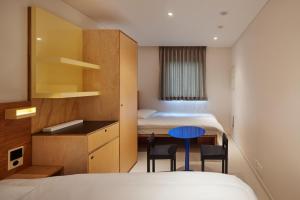 a hotel room with two beds and a table and chairs at Mangrove Sinseol in Seoul