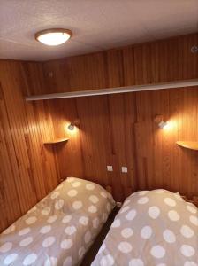 ロクビリエールにある2 pièces proche cure thermaleのベッド1台が備わる小さな客室で、壁は木製です。
