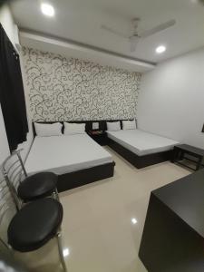 希萨尔Hotel Shree的有两张床、一张桌子和几把椅子的房间