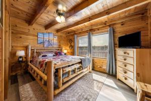 a log cabin bedroom with a bed and a flat screen tv at Serenity, A Rustic Log Cabin Retreat in Sevierville