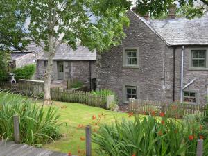 an old stone house with a garden in front of it at The Rockery in Shap