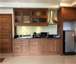eine Küche mit Holzschränken und einem schwarzen Kühlschrank in der Unterkunft Khanom Beach Residence Condo - Spacious 1-bedroom in Khanom