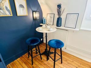 une petite table et deux tabourets bleus dans une pièce dans l'établissement Appart Rouen Jardin des plantes, à Rouen
