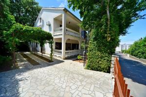 una gran casa blanca con un árbol y una acera en Apartments Karmelić, en Malinska