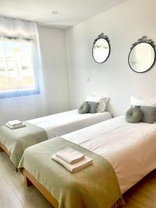 2 camas en una habitación blanca con 2 espejos en Porto Smart Apartments Comfort, en Perafita