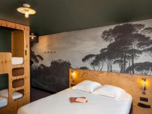 1 dormitorio con 1 cama con una pintura en la pared en Eklo Lyon en Vénissieux