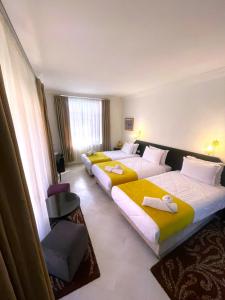 una habitación de hotel con 3 camas y una silla en Majorel Perle Hôtel Riad Restaurant Picine & Spa, en Marrakech