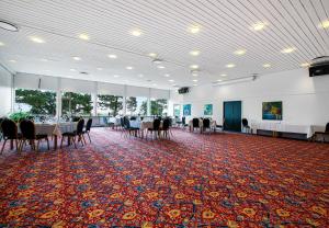 une salle de banquet avec des tables et des chaises sur un tapis dans l'établissement Hotel/ Apartments Marina, à Grenå