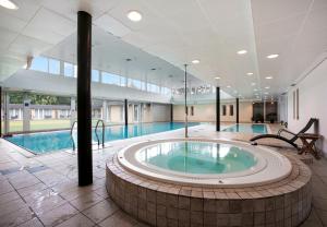 une grande piscine avec un bain à remous au milieu d'un bâtiment dans l'établissement Hotel/ Apartments Marina, à Grenå