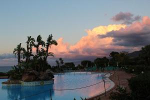 a swimming pool at a resort with a sunset at Rais Gerbi Appartamento in Pollina