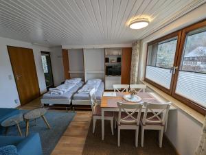 Menzenschwand-HinterdorfにあるC1 Albmatte-FEWO Sauna, Hallenbad Außenbecken Massagen nebenanのベッド、テーブル、椅子が備わる客室です。