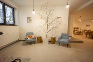ein Wohnzimmer mit 2 Stühlen und einem Baum an der Wand in der Unterkunft Penzion 7 pokojů in Znojmo