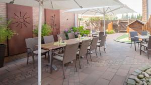 a patio with tables and chairs and an umbrella at Landhotel Jäckel in Halle Westfalen