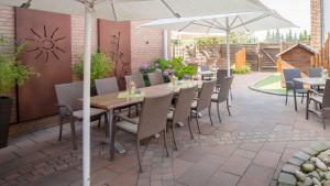 een patio met tafels en stoelen en een parasol bij Landhotel Jäckel in Halle Westfalen