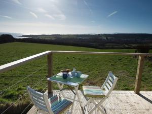 a table and two chairs on a deck with a view at Ty Arwen in Penrhos-Lligwy