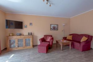 a living room with two red chairs and a tv at Villa-Senta-Apartment-8 in Kühlungsborn