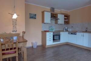 a kitchen with blue cabinets and a table and a dining room at Villa-Senta-Apartment-10 in Kühlungsborn