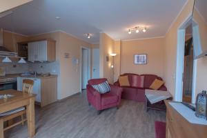 a living room with a red couch and a kitchen at Villa-Senta-Apartment-13 in Kühlungsborn +15 photos
