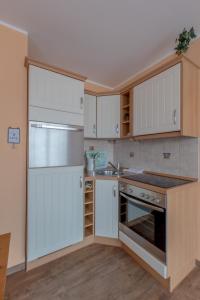 uma cozinha com armários brancos e um forno com placa de fogão em Villa-Senta-Apartment-14 em Kühlungsborn