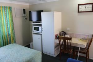 a small room with a bed and a desk with a microwave at Motel Northview Mackay in Mackay