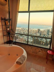 a bath tub in a bathroom with a large window at Amazing Panorama Bay view 3 room flat in Haifa
