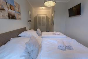 - 2 lits dans une chambre avec des draps blancs et des serviettes dans l'établissement Villa-Borwin-Apartment-12, à Kühlungsborn