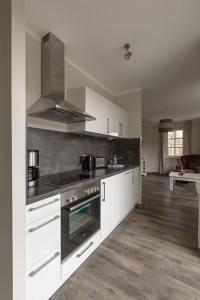a kitchen with white cabinets and a stove top oven at Villa-Borwin-Apartment-13 in Kühlungsborn