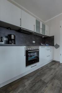 Villa-Borwin-Apartment-18 في كولونغسبورن: مطبخ فيه دواليب بيضاء وفرن