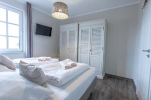 Villa-Borwin-Apartment-18 في كولونغسبورن: سريرين في غرفة نوم بجدران بيضاء ونافذة