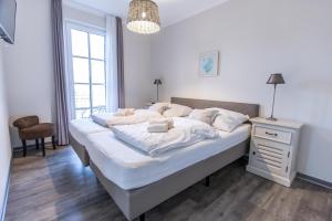 1 dormitorio con 1 cama con sábanas blancas y mesita de noche en Villa-Borwin-Apartment-10, en Kühlungsborn