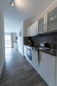 a kitchen with white cabinets and a wooden floor at Villa-Borwin-Apartment-9 in Kühlungsborn