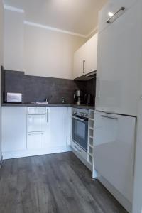 Il comprend une cuisine blanche avec des appareils électroménagers blancs et du parquet. dans l'établissement Villa-Borwin-Apartment-8, à Kühlungsborn