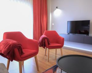 a living room with two red chairs and a tv at Parta Apartment in Pristina