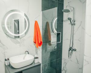 a bathroom with a sink and a shower with a mirror at Parta Apartment in Pristina