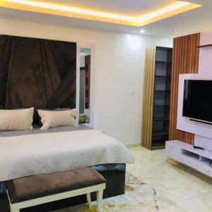 a bedroom with a bed and a flat screen tv at Beautiful 4-Bedroom House in Ogombo