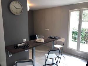 a table with chairs and a clock on a wall at Echoppe Bordelaise chaleureuse in Bordeaux