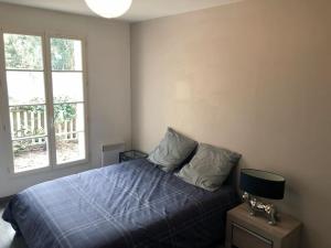 a bedroom with a bed with a blue comforter and two windows at Echoppe Bordelaise chaleureuse in Bordeaux