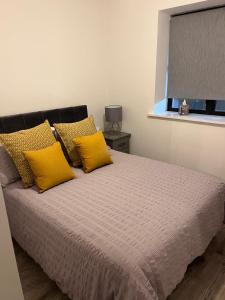 a bedroom with a bed with yellow pillows and a window at 2 Bed Gated Apartment Westport in Westport