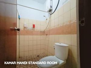 a bathroom with a toilet in a tiled room at My Place Guest House Manado in Manado