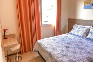 um quarto com uma cama, cortinas cor de laranja e uma janela em Residencial Flat Villa Rosa em Itapetininga