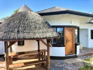 a small hut with a thatch roof and a door at Garden Cottage Guest House in De Aar