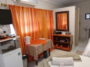 a room with a bed and a table and a mirror at Garden Cottage Guest House in De Aar