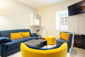 a living room with a blue couch and yellow chairs at Le Grand Banc - Maison typique pour 6 in Erquy