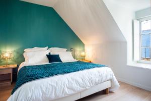 a bedroom with a large bed with a green wall at Le Grand Banc - Maison typique pour 6 in Erquy