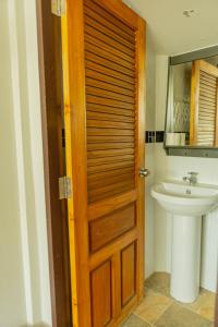 a bathroom with a wooden door and a sink at Apinya Resort Bangsarey in Ban Tao Than