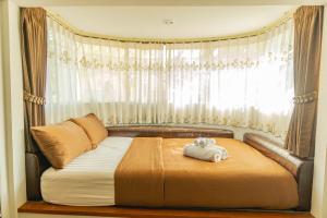 Una cama en un dormitorio con una ventana con un osito de peluche. en Apinya Resort Bangsarey en Ban Tao Than