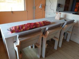 een houten tafel met stoelen en een tafel met een parasol bij Safaritent Ranger Lodge in Kesteren