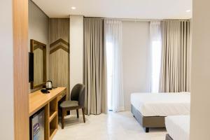 a hotel room with a bed and a desk and a television at The Manaoag Hotel in Manaoag